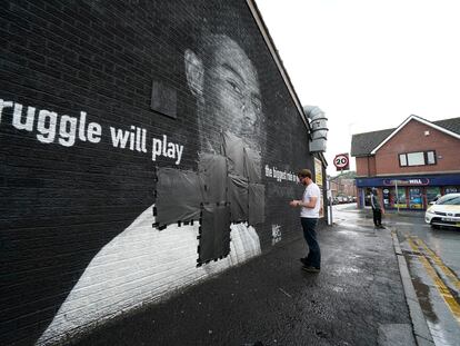 Un operario tapaba este lunes con cinta negra los insultos escritos en el mural de homenaje al jugador Marcus Rashford, en Mánchester (Inglaterra).