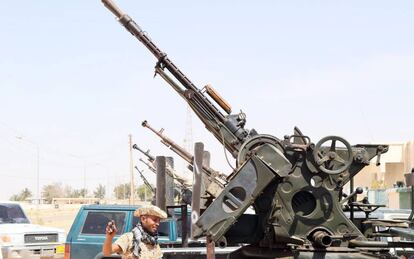 Un miembro de las milicias libias leales al Gobierno de Unidad, delante de varias armas situadas en el puesto de control de Abú Grain, al este de Misrata, el 18 de mayo.