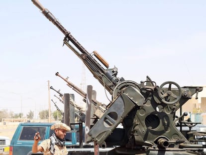 Un miembro de las milicias libias leales al Gobierno de Unidad, delante de varias armas situadas en el puesto de control de Ab&uacute; Grain, al este de Misrata, el 18 de mayo.
 