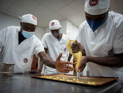 Moustapha Thiandoum, en el centro, junto a Abdoulaye Kande, con mascarilla azul, y Mamadou Diouf atienden al taller de formación en panadería que realizaron gracias a Nostos África para formarse y así poder volver a Senegal y montar su propia pastelería.