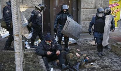 Policía antidisturbios rodea un par de manifestantes heridos.