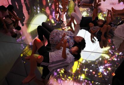 Visitantes contemplan la instalación 'Floating in the Falling Universe of Flowers' ('Flotando en el universo de las flores que caen') presentado por el colectivo artístico teamLab en el evento 'A World of Wonders' en la exposición Odaiba Minna no YUME-TAIRIKU 2016, en Tokio (Japón).