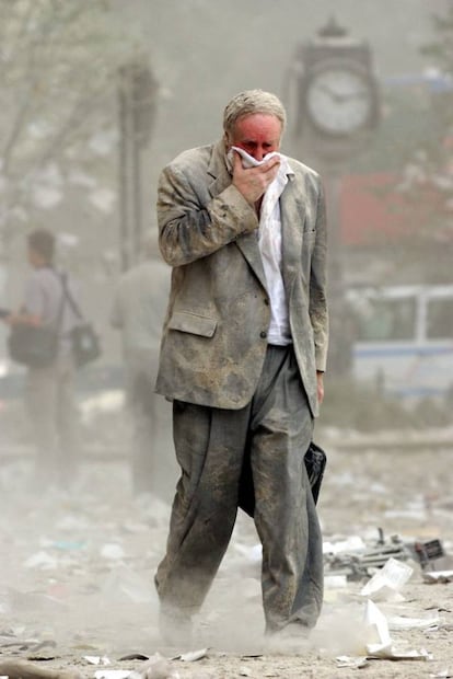 Un ciudadano cubierto de polvo, anda con la nariz y boca tapadas para poder respirar, tras el desplome de las Torres Gemelas.