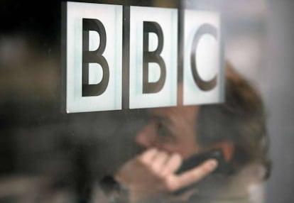 Un hombre habla por teléfono tras un cristal con el logo de la BBC