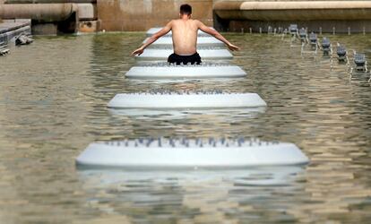 Un hombre se refresca en una fuente pública debido a las altas temperaturas que estos días se registran en París (Francia).