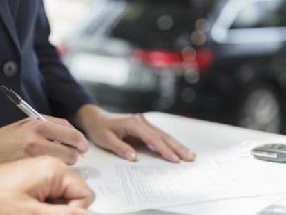 Un cliente firma un contrato financiero en un concesionario de coches.  