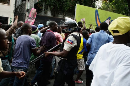 Un policía haitiano camina entre los manifestantes en el centro de Puerto Príncipe, a favor del candidato derrotado el cantante, Michel Martelly.