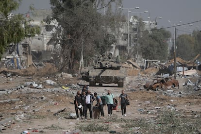 Palestinos huyen por la carretera de Salah al Din mientras un carro de combate israelí les apunta, el 24 de noviembre de 2023. 