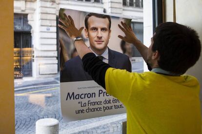 Un votante coloca un cártel de apoyo a Emmanuel Macron.