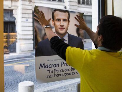 Un votante coloca un cártel de apoyo a Emmanuel Macron.