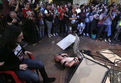 Tras un espectacular movimiento, Padre Paolo se duele en el suelo tras ser lanzado por sus contrincantes sobre un montón de mesas apiladas fuera del ring.