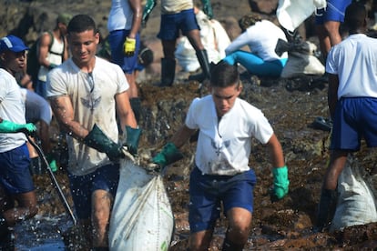 Homens da Marinha também se misturaram aos voluntários civis para retirar o óleo acumulado da praia de Itapuama, nesta terça-feira.