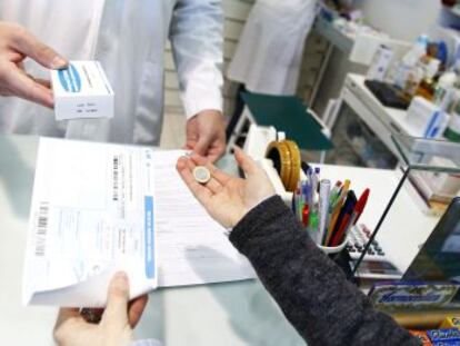 Un empleado de una farmacia madrile&ntilde;a atiende a un cliente.