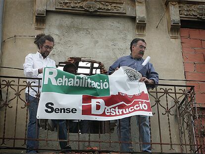 Faustino Villora (derecha) y otro miembro de Salvem El Cabanyal, ayer, colocan una pancarta en uno de los edificios pendiente de derribo.