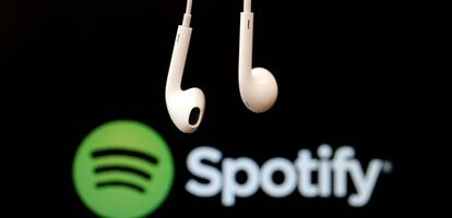 Unos auriculares delante del logotipo de Spotify.