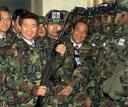 El presidente electo de Corea del Sur, Roh Moo-hyun, posa con una ametralladora en su visita a una base militar.