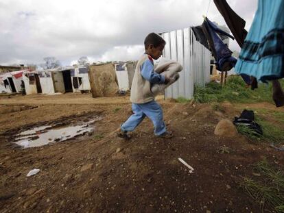 Un niño sirio carga ropa donada por Inditex en un campo de refugiados en la población de al-Bireh, al norte de la ciudad portuaria de Trípoli, en Líbano