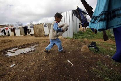 Un niño sirio carga ropa donada por Inditex en un campo de refugiados en la población de al-Bireh, al norte de la ciudad portuaria de Trípoli, en Líbano