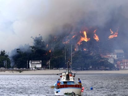 Un pesquero se aleja de la costa frente a la localidad de O &Eacute;zaro (Dumbr&iacute;a), en llamas por el incendio procedente de O Pindo.