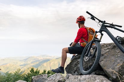 Mountain biker looking at view on bike trail in autumn mountains