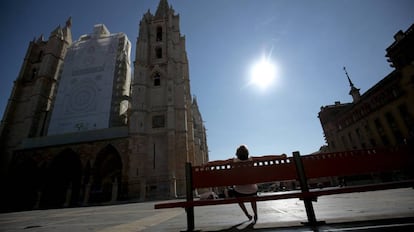 Una mujer toma el sol en un banco frente a la catedral de León.