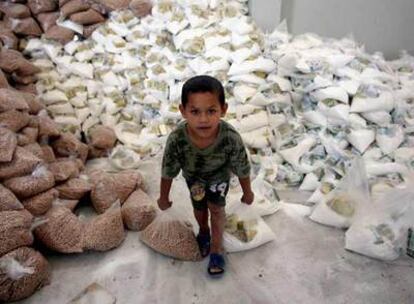 Un niño palestino recoge dos sacos de alimentos repartidos por la ONU en Beit Lahiya, Gaza.