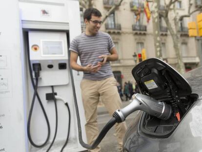 Un home recarrega el seu cotxe elèctric a Barcelona.