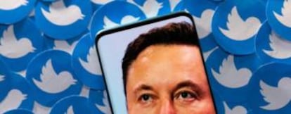 Imagen de Elon Musk en un smartphone, sobre un fondo de logos de Twitter.