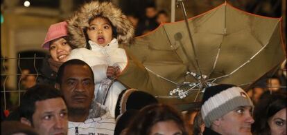 Una ni?a asiste asombrada al paseo de la Cabalgata de Reyes junto a un paraguas colocado al revs para 'pescar' los caramelos lanzados.