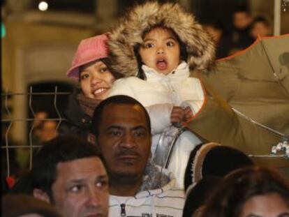 Una niña asiste asombrada al paseo de la Cabalgata de Reyes junto a un paraguas colocado al revés para 'pescar' los caramelos lanzados.