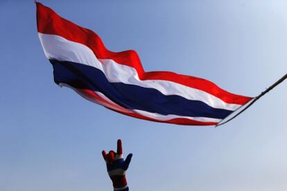 Un manifestante antigubernamental tailandés hace una muestra de la victoria que otro agita una bandera nacional durante una manifestación frente a la Casa de Gobierno en Bangkok.