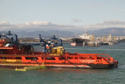 Tareas de limpieza de la mancha de hidrocarburos ante el pantalán de Repsol, en el interior del puerto de Tarragona.