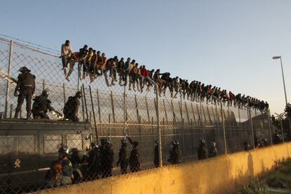 Un grupo de inmigrantes permanecen subidos a la valla de Melilla tras intentar entrar en Melilla en 2014.