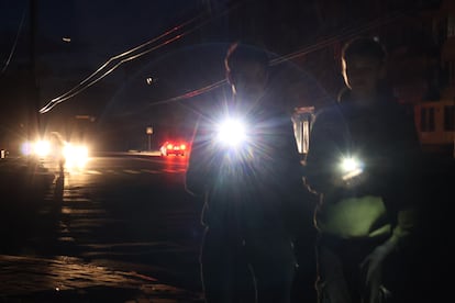 Dos peatones usan sus teléfonos para iluminar la acera de una calle de Járkov, durante un apagón. 