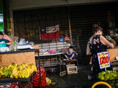 Un niño juega con un celular mientras sus padres montan trabajan en el mercado popular de La Vega, en Santiago de Chile.