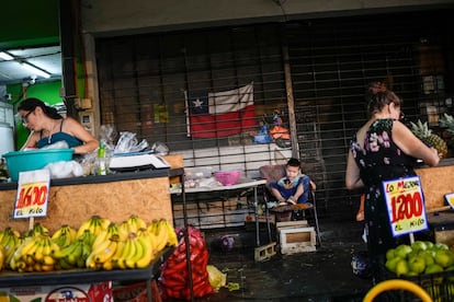 Un niño juega con un celular mientras sus padres montan trabajan en el mercado popular de La Vega, en Santiago de Chile.