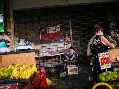 Un niño juega con un celular mientras sus padres montan trabajan en el mercado popular de La Vega, en Santiago de Chile.