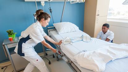 Two nurses set up a bed in a hospital.