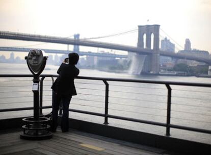 Una mujer toma una fotografía del puente de Brooklyn, sobre el East River de Nueva York