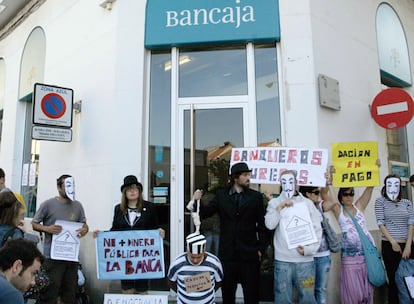 El hombre desahuciado (con traje de presidiario) y un grupo de indignados protestan ante el banco.