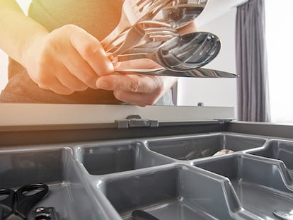 Una persona organizando los cubiertos en la cocina de su casa.