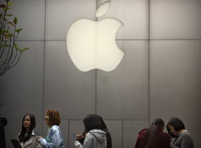 FILE - In this Friday, Oct. 20, 2017, file photo, people stand in line near an Apple Store at an outdoor shopping mall in Beijing, China. On Wednesday, Jan. 17, 2018, Apple announced it is planning to build another corporate campus and hire 20,000 workers during the next five years as part of a $350 billion commitment to the U.S. economy. (AP Photo/Mark Schiefelbein, File)