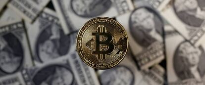 Un bitcoin junto a billetes de dólar.