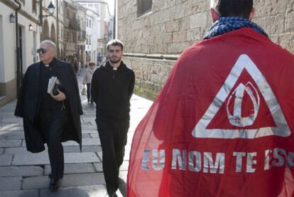 Dos religiosos se cruzan con un contrario a la visita del Papa, en las inmediaciones de la Praza do Obradoiro.