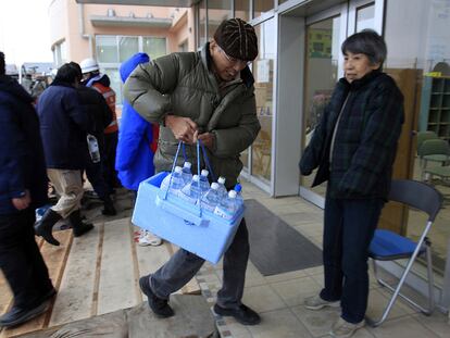 Un hombre acarrea botellas de agua de las que se ha provisto en un tanque en Urayasu, cerca de Tokio.