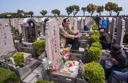 Two men sit at a grave and chat as they take part in the annual "Qingming" festival, or Tomb Sweeping Day, at a public cemetery in Shanghai on April 4, 2016. 
During Qingming, Chinese traditionally tend the graves of their departed loved ones and often burn paper offerings to honour them and keep them comfortable in the afterlife. / AFP PHOTO / JOHANNES EISELE