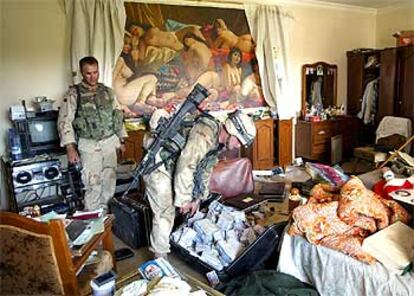 Dos soldados estadounidenses observan el dinero encontrado en la casa de un tío de Sadam al norte de Bagdad.