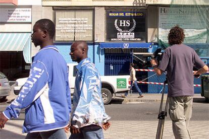 Dos inmigrantes pasan ante la sede de Huelva Solidaria, cinco de cuyos miembros han sido detenidos por estafa.