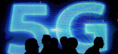 Visitantes pasan junto a un logo de 5G en el Mobile World Congress Barcelona 2017.