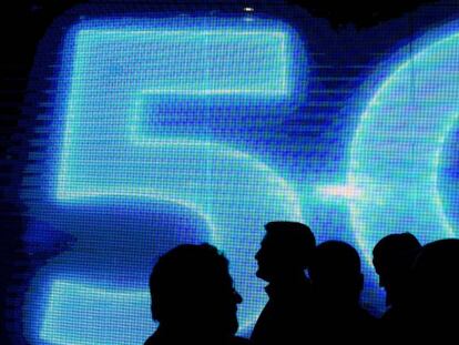 Visitantes pasan junto a un logo de 5G en el Mobile World Congress Barcelona 2017.